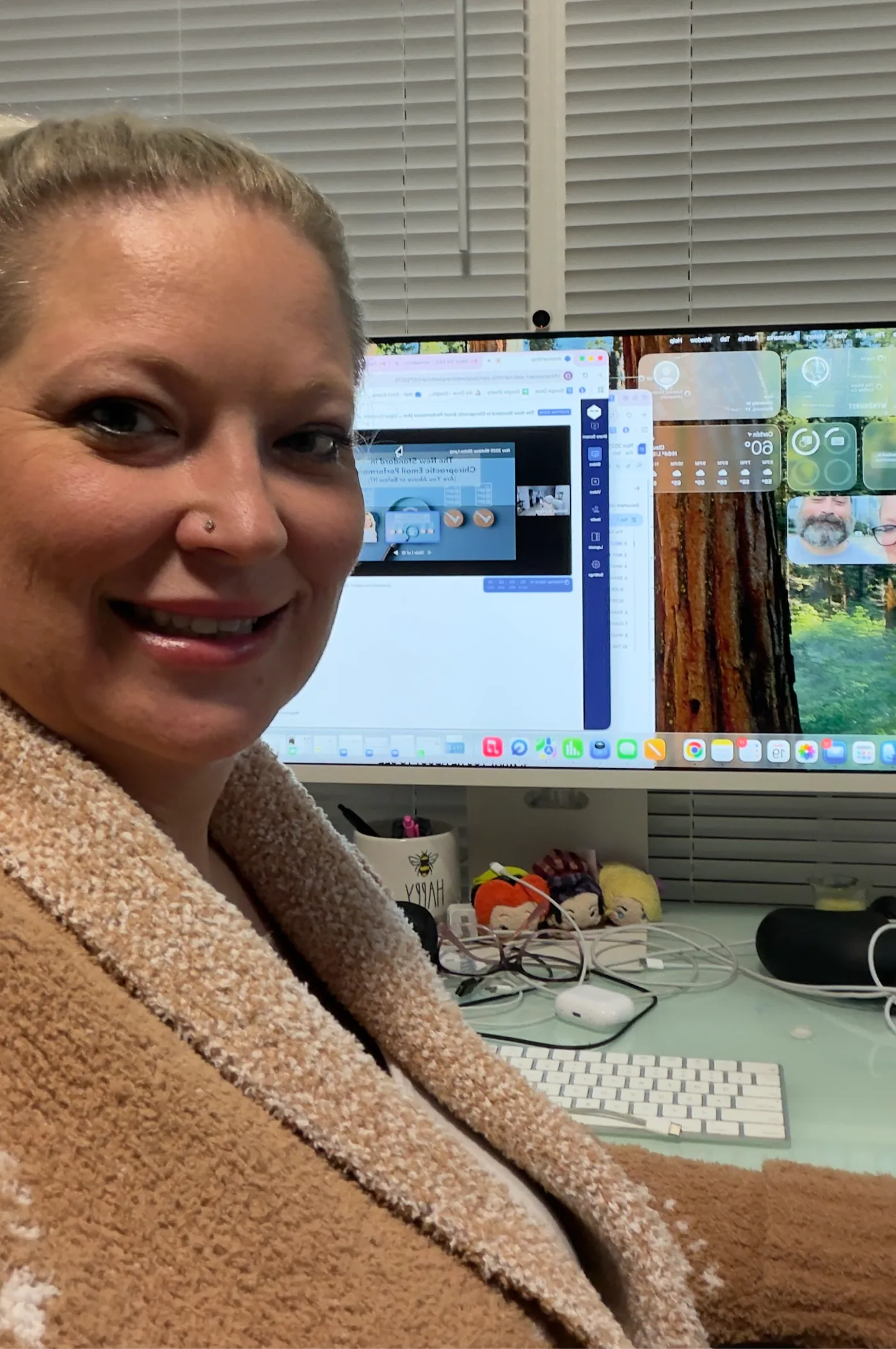 Nerissa Brumley sitting at her desk smiling, with a computer screen behind her showing a Chiro Connect dashboard and browser tabs.