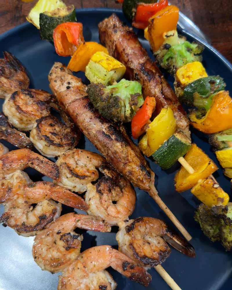 Shrimp, sausage, and vegetable kabobs arranged on a blue plate